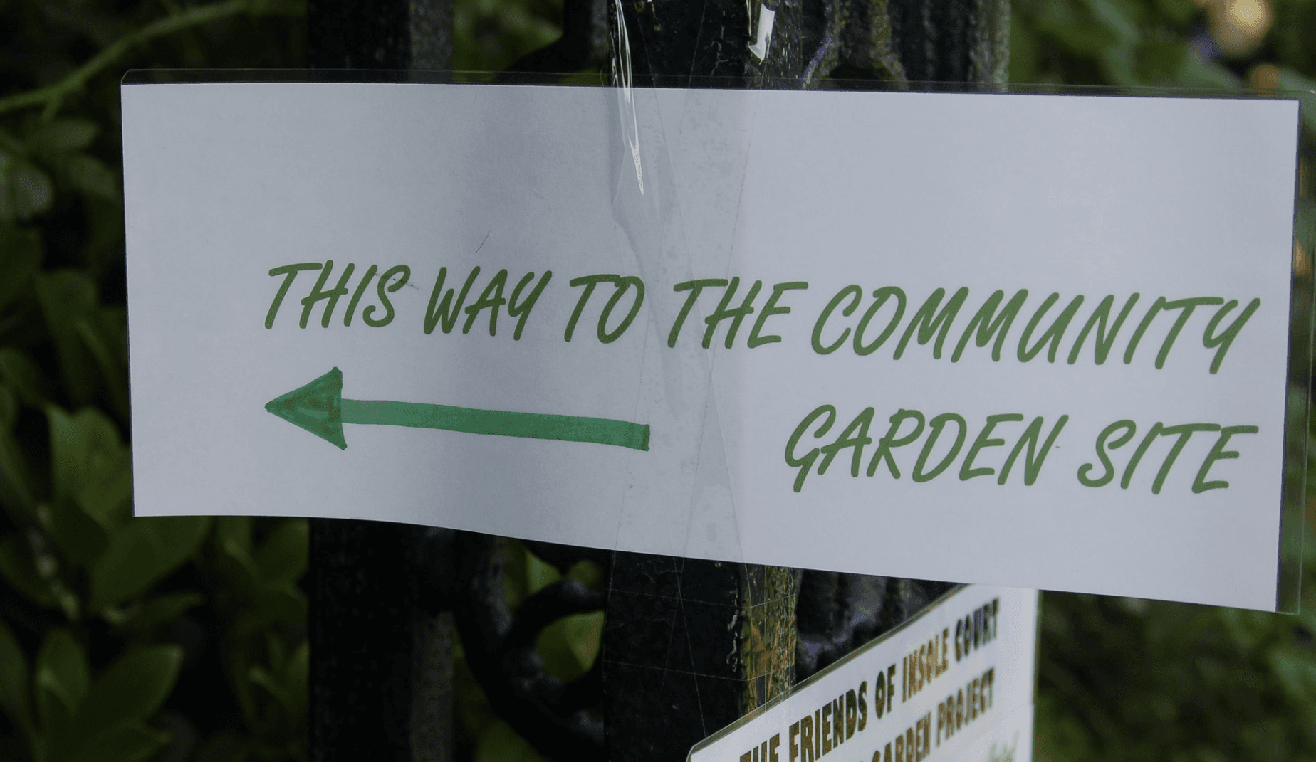 Printed sign with green arrow and text "This way to the community garden site"